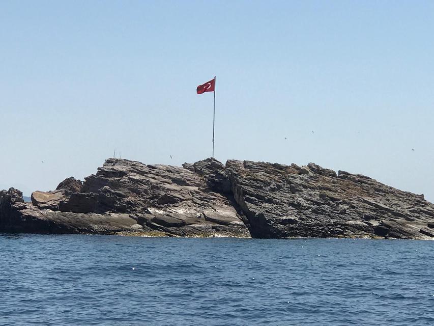 Muğla'nın Bodrum ilçesindeki Yassıkaya Adası'nda dalgalanan Türk bayrağının, ipinin koparak düşmesi ihbarı üzerine Sahil Güvenlik ekibi, bayrağı yeniden göndere çekti. ( Sahil Güvenlik - Anadolu Ajansı )